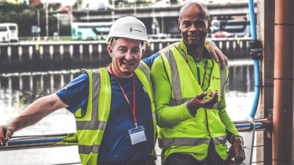 Two men in the construction trade, wearing high-visibility vests
