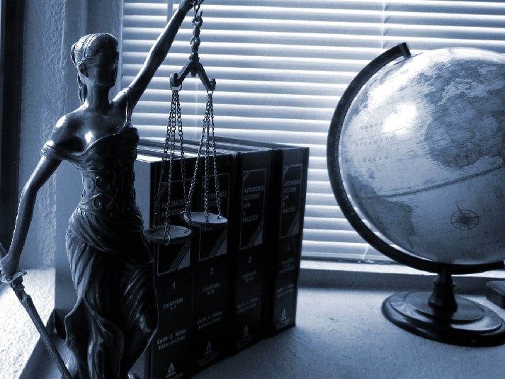 Lady Justice on a table with law books and a globe
