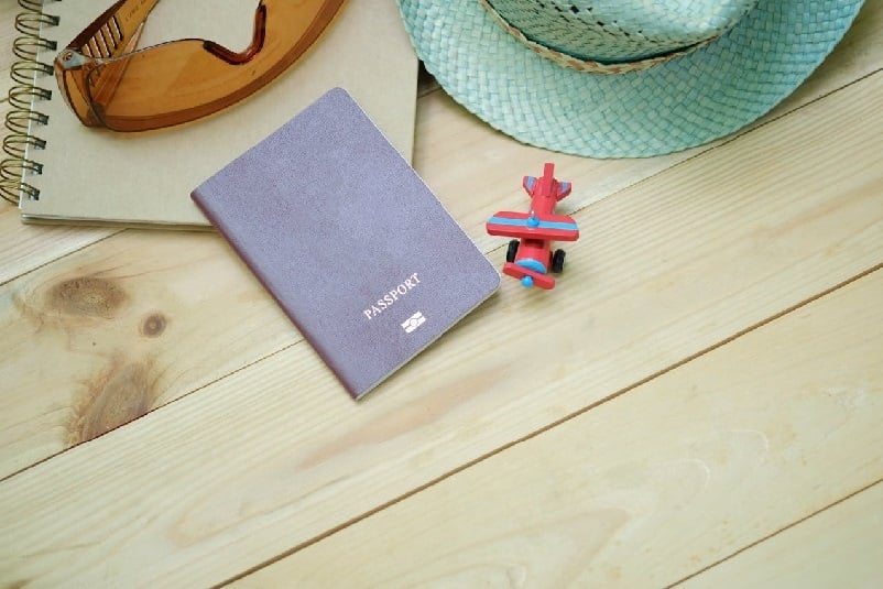 Passport on desk with toy plane and notebook